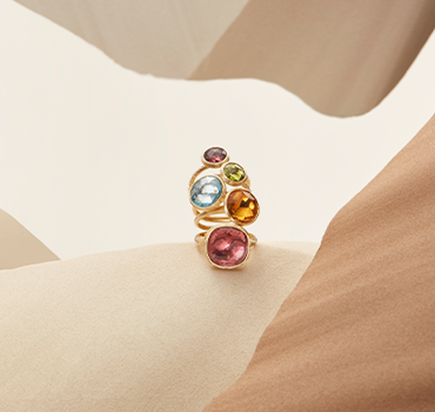 Stacked Marco Bicego rings resting on a sandy background.